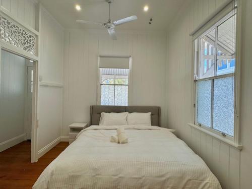 Cama grande en habitación blanca con 2 ventanas en East Brisbane Federation-Style Pool Villa, en Brisbane