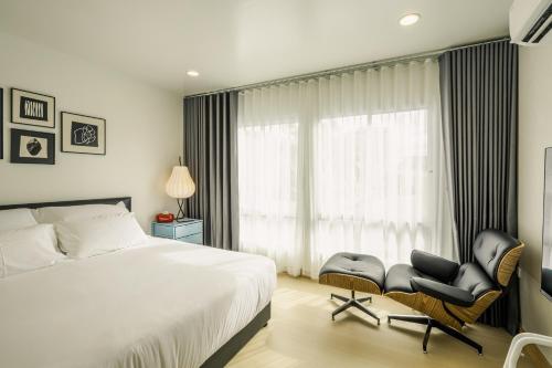 a bedroom with a bed and a chair and a window at anhaus chiangrai in Chiang Rai