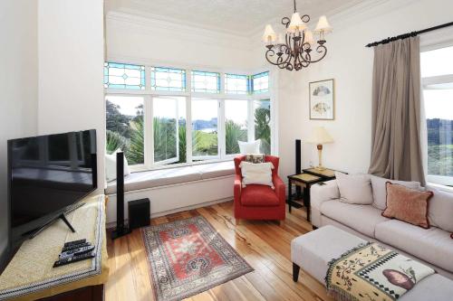 Crescent Villa - Stay Waiheke في Ostend: غرفة معيشة مع أريكة وتلفزيون
