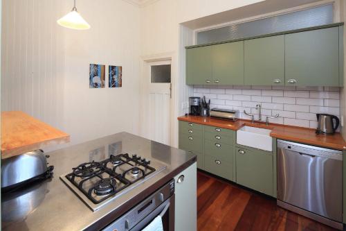 Crescent Villa - Stay Waiheke في Ostend: مطبخ مع دواليب خضراء وموقد الفرن العلوي