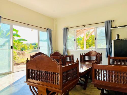 ein Esszimmer mit Tisch und Stühlen und Fenstern in der Unterkunft Mountain view Villa Private Tropical Garden in Chiang Dao