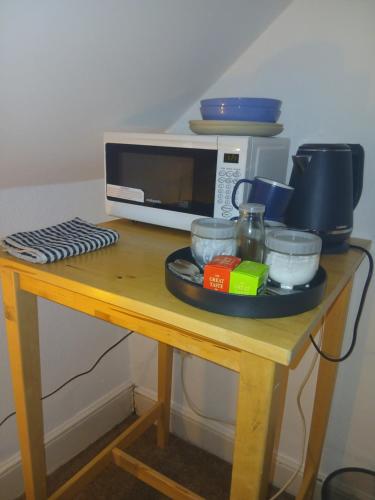 ein Tisch mit einer Mikrowelle und einigen Schüsseln in der Unterkunft Uplands Room in Sketty