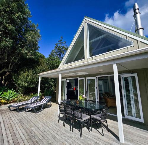 a patio with a table and chairs on a deck at Viewpoint - Stay Waiheke in Onetangi