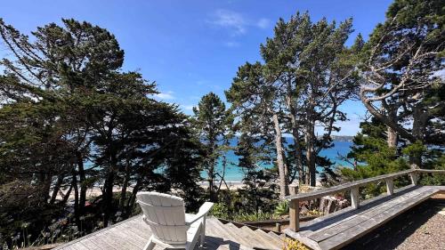 a white chair sitting on a wooden deck overlooking the ocean at Viewpoint - Stay Waiheke in Onetangi