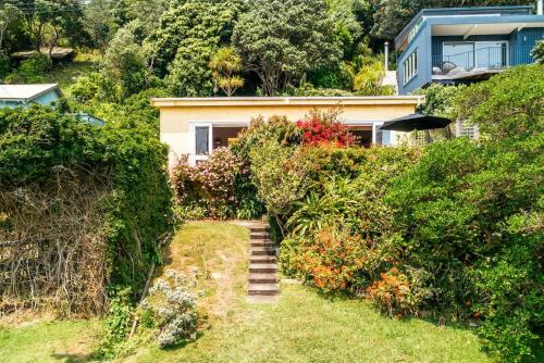 a house on a hill with stairs in front of it at Sunshine Cottage by the Sea - Stay Waiheke in Onetangi
