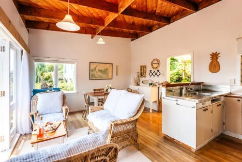 a kitchen and living room with wooden ceilings at Sunshine Cottage by the Sea - Stay Waiheke in Onetangi