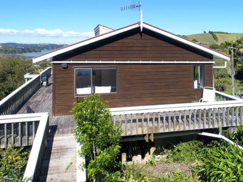 a house with a wooden porch and a balcony at Church Bay Views - Stay Waiheke in Oneroa