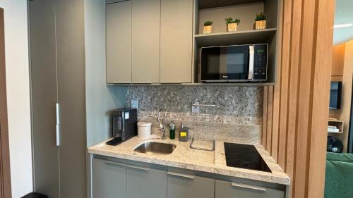una cocina con fregadero y microondas en Charming apartment with balcony a few minutes apto from Barra, en Salvador