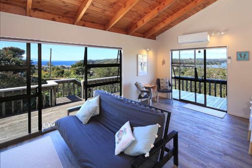 een woonkamer met een blauwe bank en een balkon bij Church Bay Views - Stay Waiheke in Oneroa