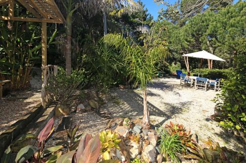 a garden with two chairs and an umbrella at La Maisonette - Stay Waiheke in Onetangi