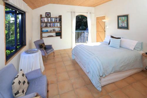 a bedroom with a bed and a table and a chair at La Maisonette - Stay Waiheke in Onetangi