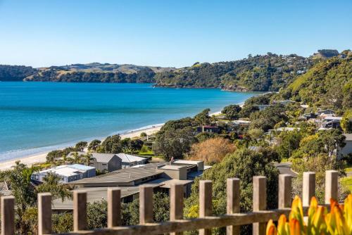 a view of a beach from a fence at Wavesong - Stay Waiheke in Onetangi