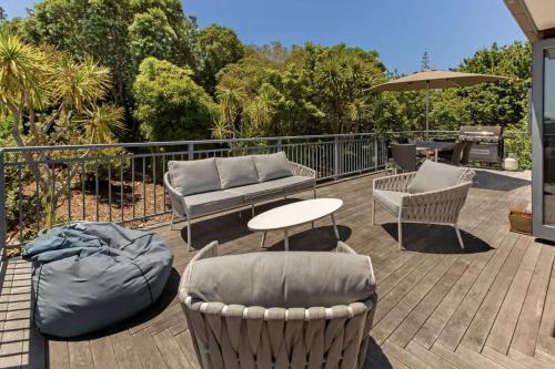 a patio with chairs and a couch and a table at The Cove at Little O - Stay Waiheke in Oneroa