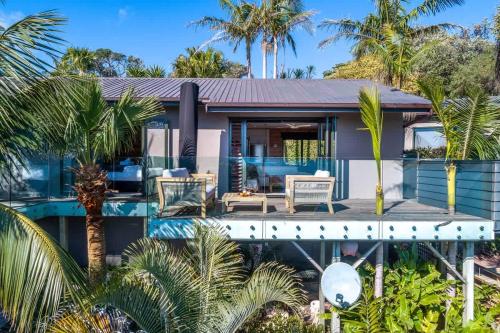 een huis met een zwembad en palmbomen bij Palms on Kennedy Point - Stay Waiheke in Te Whau Bay
