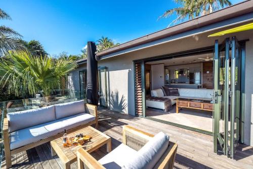 een patio met een bank en een tafel bij Palms on Kennedy Point - Stay Waiheke in Te Whau Bay