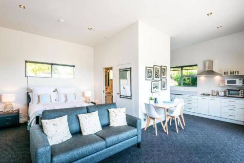 a living room with a blue couch and a kitchen at Delamore Cove - Kauri - Stay Waiheke in Matiatia Bay