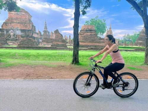 a woman riding a bike in front of temples at Phiphu Art and Gallery Boutique Sukhothai in Sukhothai