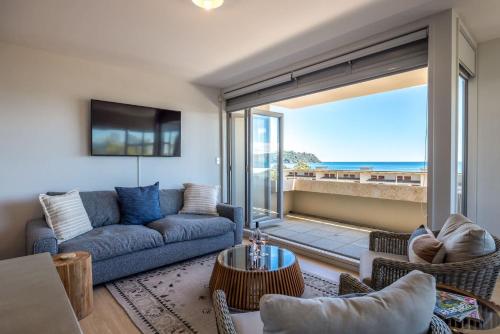 a living room with a couch and a view of the ocean at The Sands - Apartment 5 - Stay Waiheke in Onetangi