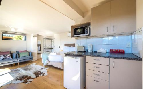 a kitchen with a counter top and a living room at Aqua Sands #1 - Stay Waiheke in Oneroa