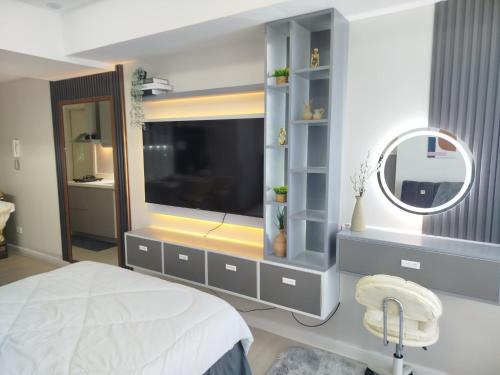 een slaapkamer met een grote televisie en een spiegel bij Z Crib - Azure North in San Fernando
