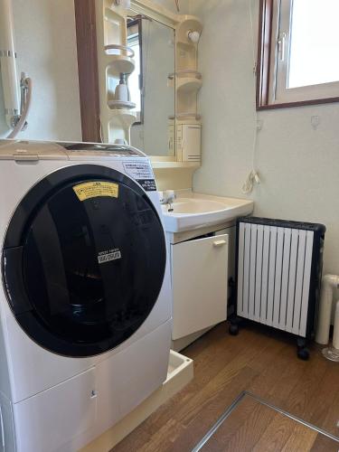 a washing machine in a bathroom with a sink at Pine House in Rankoshi