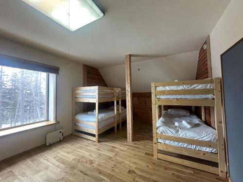 een kamer met 3 stapelbedden en een raam bij Pine House in Rankoshi