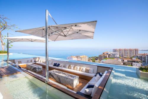 a swimming pool with a couch and an umbrella at Pier 57 Romantic Zone Luxury Condo 209 in Puerto Vallarta
