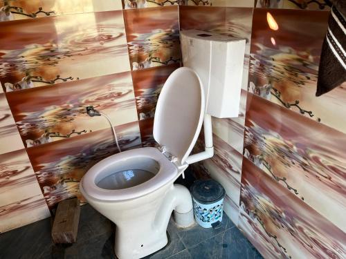 La salle de bains est pourvue de toilettes et d'une peinture murale. dans l'établissement Hill View Cottage, à Chakrata