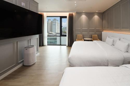 a hotel room with two beds and a flat screen tv at Hound Hotel Mokpo Peace Plaza in Mokpo