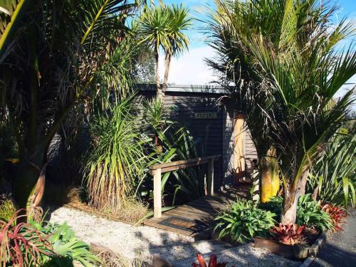 a garden with palm trees and a small building at Tutiri in Oneroa - Stay Waiheke in Oneroa