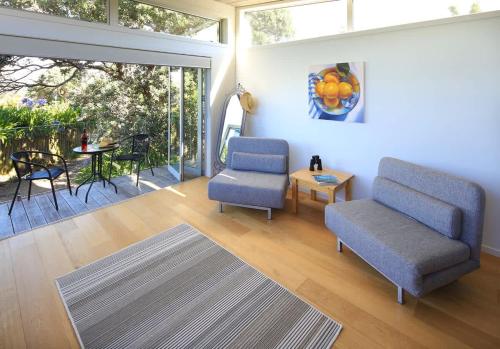 a living room with two chairs and a table at Tutiri in Oneroa - Stay Waiheke in Oneroa