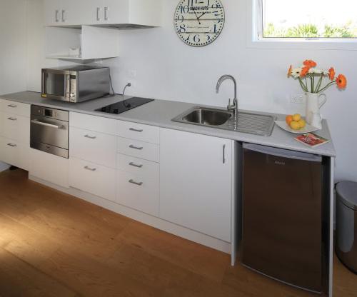 a white kitchen with a sink and a dishwasher at Tutiri in Oneroa - Stay Waiheke in Oneroa
