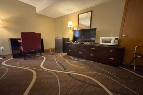 a hotel room with a television and a desk with a chair at Super 8 by Wyndham Normal Bloomington in Bloomington
