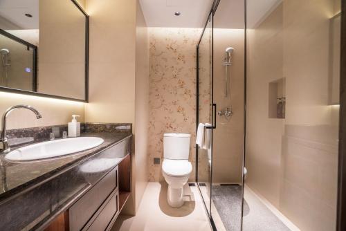Un baño con inodoro, lavabo y ducha. en Lijiang Wangfu Hotel, en Lijiang