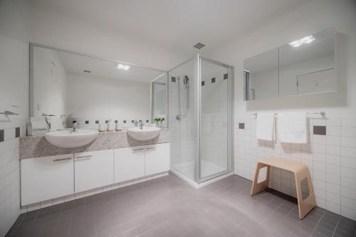 a white bathroom with two sinks and a shower at Heart of Hobart | CBD Apartment & Parking in Hobart