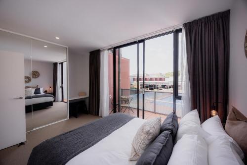 a bedroom with a large bed and a balcony at Heart of Hobart | CBD Apartment & Parking in Hobart