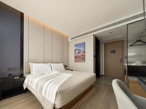 ein Schlafzimmer mit einem großen weißen Bett und einem Fernseher in der Unterkunft 上海静安寺西康路亚朵酒店 in Shanghai