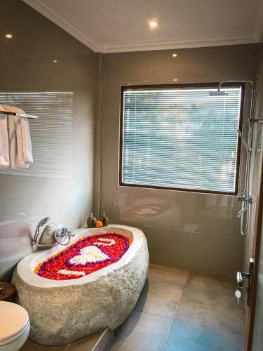 een badkamer met een groot stenen bad en een raam bij Kemala Hospitality in Tegalalang