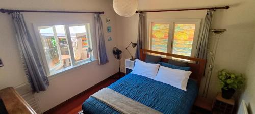 a bedroom with a blue bed and a window at Wainui bush retreat in Kaeo