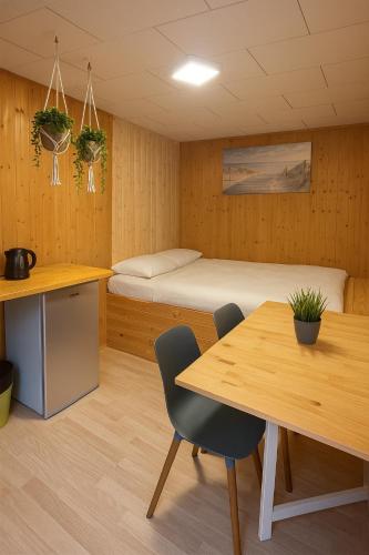 a room with a bed and a table and chairs at Camping Standard Bungalow Ferienwohnung auf Rügen - bis 5 Personen - nur 100m zum Naturstrand - mitten im Wald - Familien und Hunde herzlich willkommen - Feriensiedlung Schwalbennest in Dranske