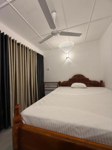 a bedroom with a bed with a ceiling fan at White place in Ahangama