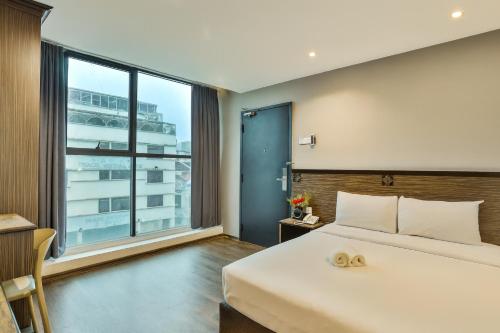 a bedroom with a large bed and a large window at Q Collection Macalister formerly known as Apple Hotel Penang in George Town