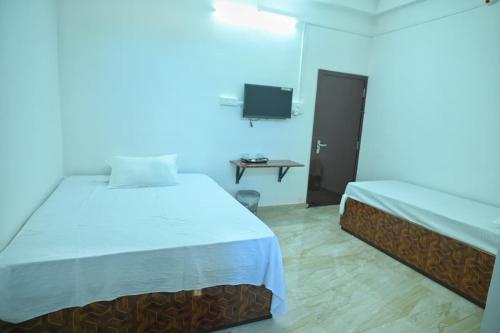a bedroom with two beds and a table with a tv at Hotel Tricon Residency in Guwahati