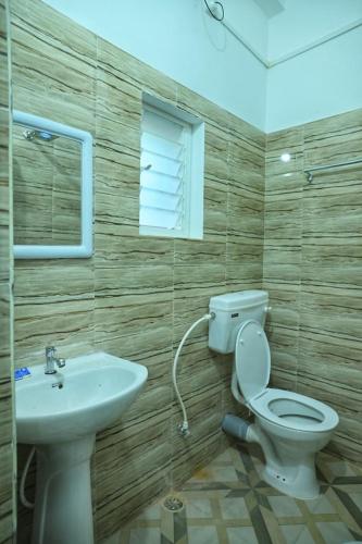 a bathroom with a toilet and a sink at Hotel Tricon Residency in Guwahati
