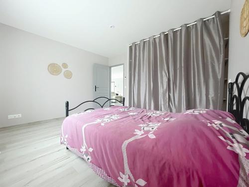 een slaapkamer met een roze deken op een bed bij Maison Lahourcade in Lahourcade
