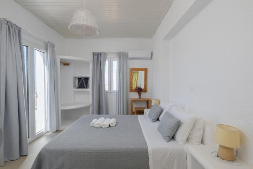 een witte slaapkamer met een bed en een groot raam bij Vavoulas Village in Mikri Vigla