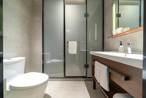 une salle de bains avec toilettes et douche en verre dans l'établissement Hanting Hotel Shanghai Jiaotong University Jiangchuan Road Subway Station 2, à Shanghai