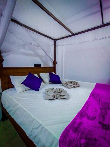 Una cama en una tienda de campaña con sábanas y almohadas moradas. en Lyra Mirissa, en Mirissa
