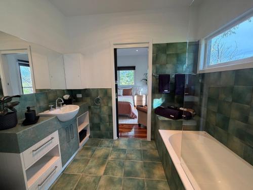 een badkamer met een bad en een wastafel en een ligbad bij Vineyard Cottage at Oakdene in Wallington