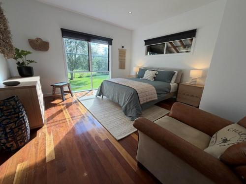 een slaapkamer met een bed en een bank bij Vineyard Cottage at Oakdene in Wallington